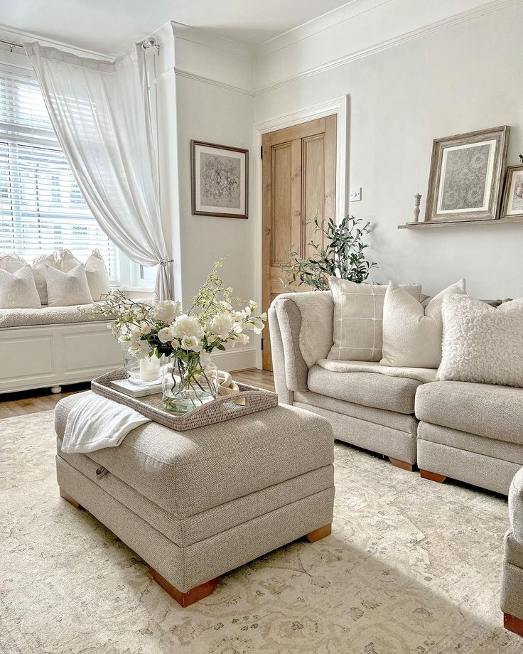 a living room filled with furniture and flowers on top of a table in front of a window