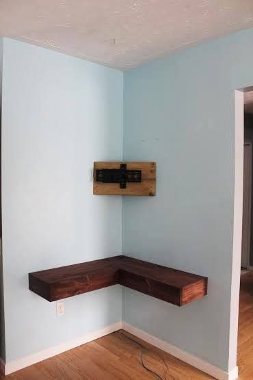 an empty room with blue walls and wooden shelves on the wall, along with wood flooring