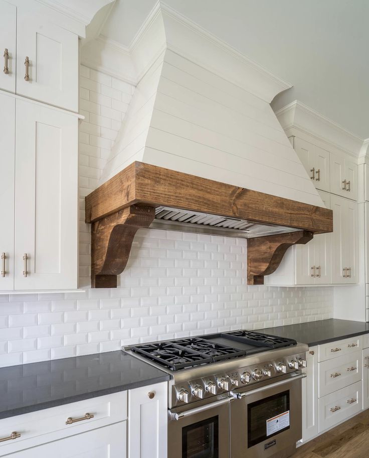 a stove top oven sitting inside of a kitchen next to white cabinets and counter tops