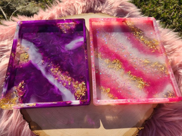 two trays sitting on top of a wooden table covered in purple and gold paint