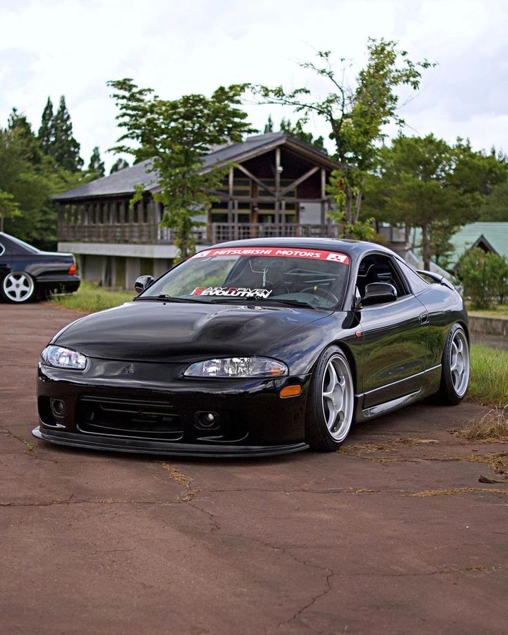 a black car parked on top of a parking lot in front of a wooden building