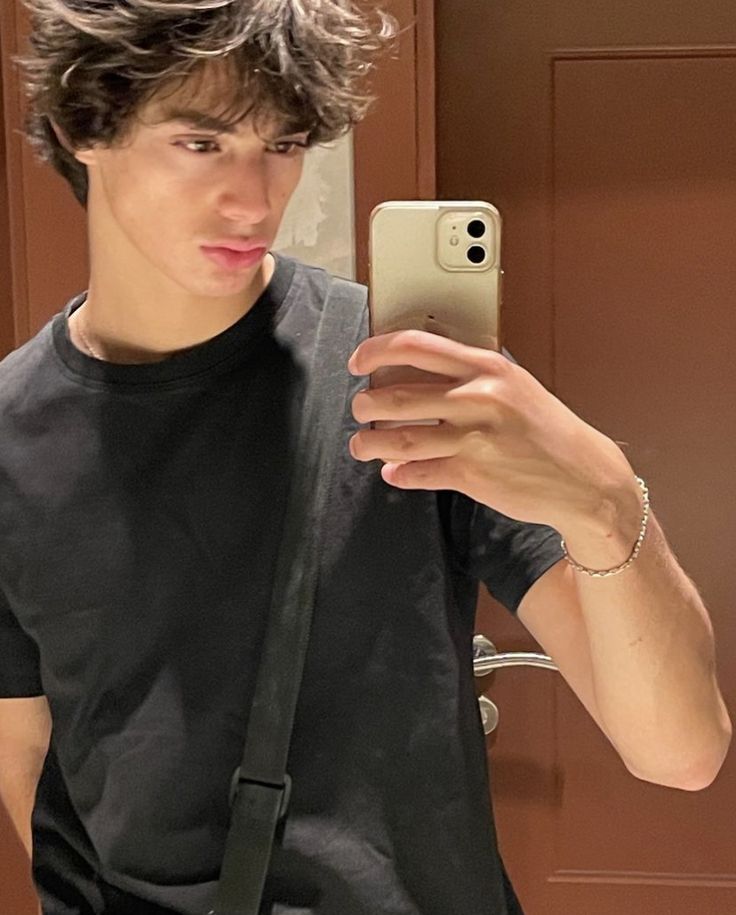 a young man taking a selfie in front of a mirror with his cell phone