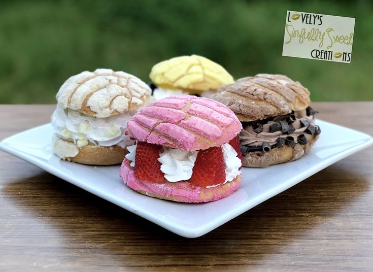 three pastries on a white plate sitting on a wooden table with a sign in the background