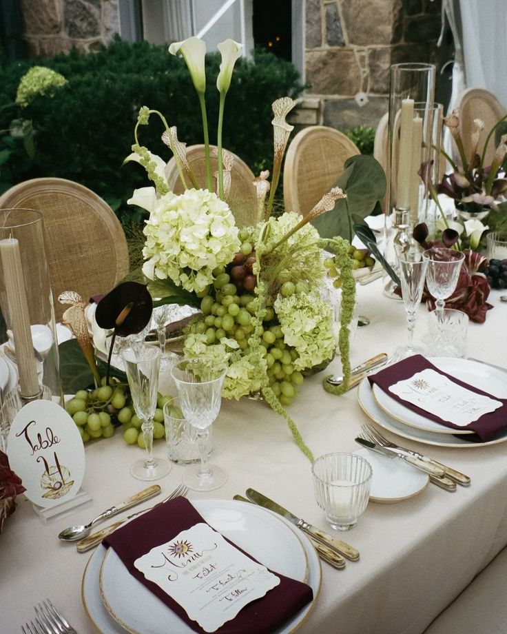 the table is set with white and burgundy place settings, silverware, and flowers