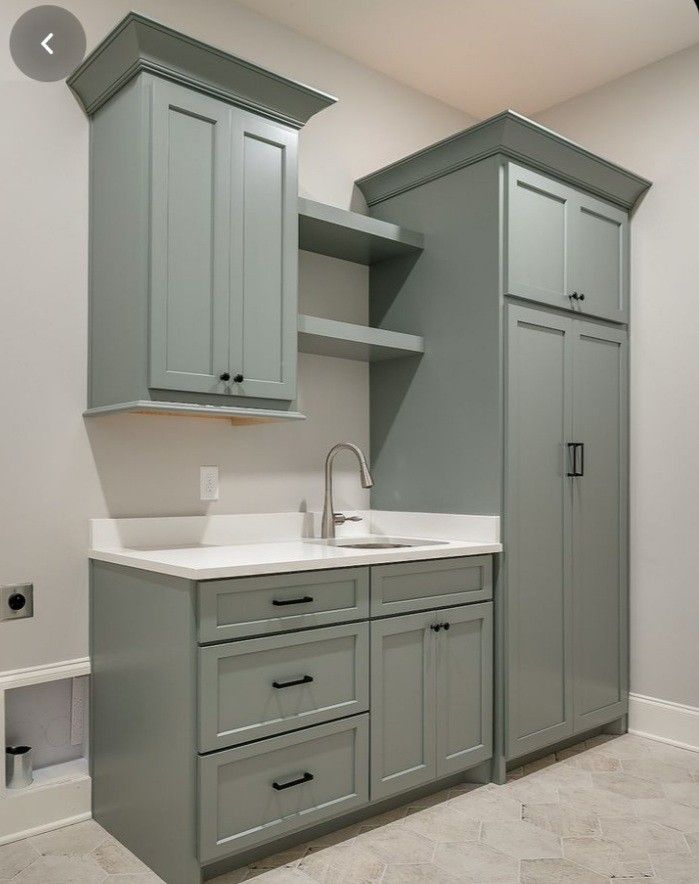 an empty kitchen with gray cabinets and white counter tops in the middle of the room