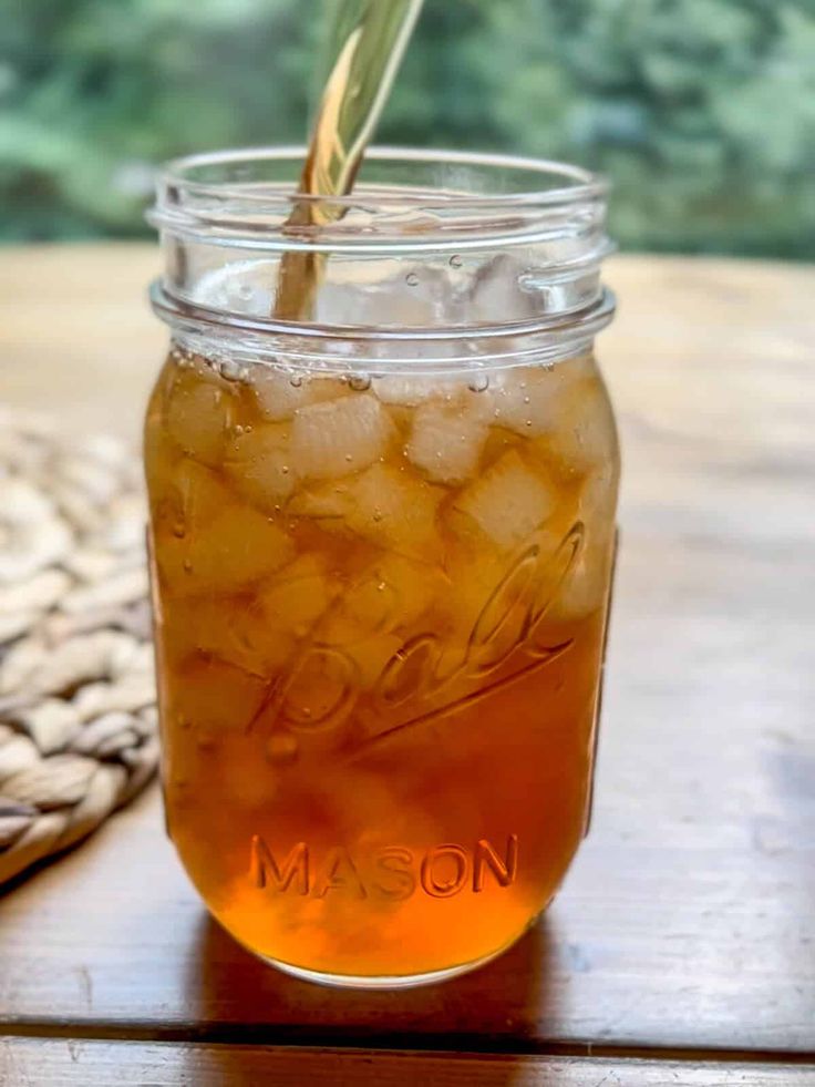 a mason jar filled with ice sitting on top of a wooden table