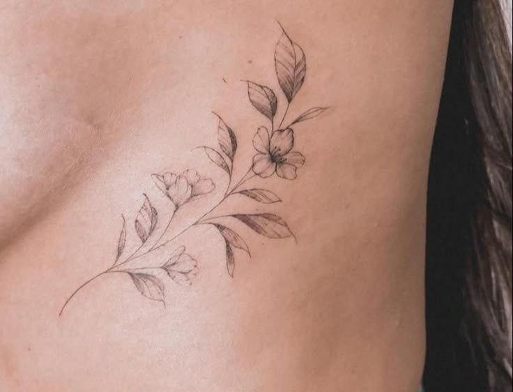 a close up of a woman's stomach with flowers tattooed on the side of her body