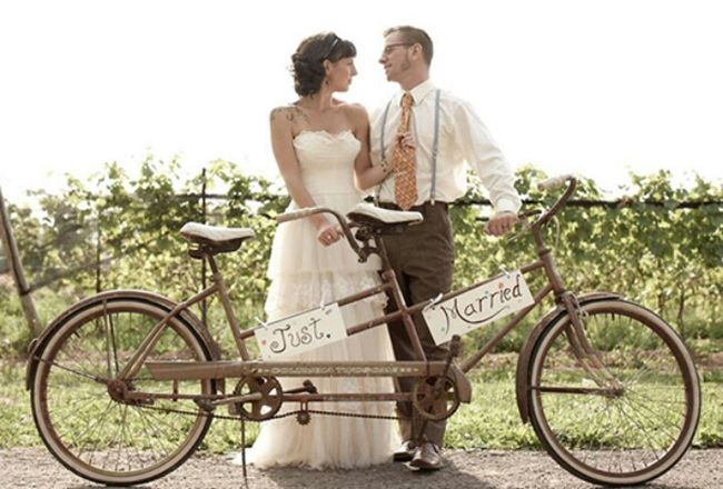 a bride and groom standing next to their bike