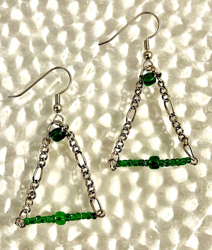 Triangular wire structure with glass beads and an ear wire. Party Wire Wrapped Glass Jewelry, Party Glass Jewelry Wire Wrapped, Party Earrings With Dangling Glass Beads, Glass Beaded Dangle Earrings For Parties, Wire Wrapped Metal Earrings For Party, Party Wire Wrapped Metal Earrings, Green Metal Beaded Party Earrings, Nickel-free Metal Beaded Earrings For Party, Green Metal Beaded Earrings For Party