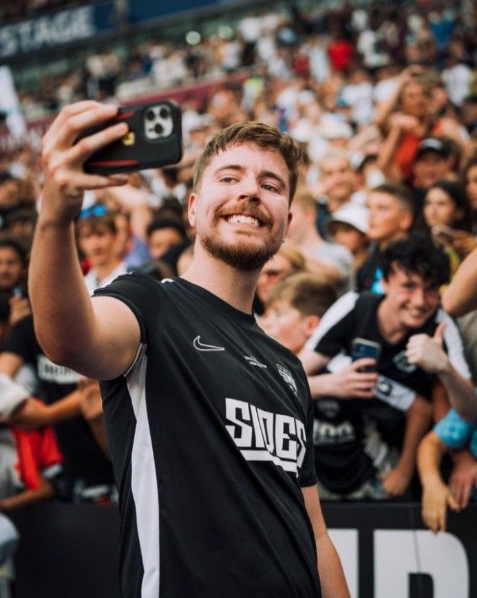 a man taking a selfie with his cell phone in front of an audience at a sporting event