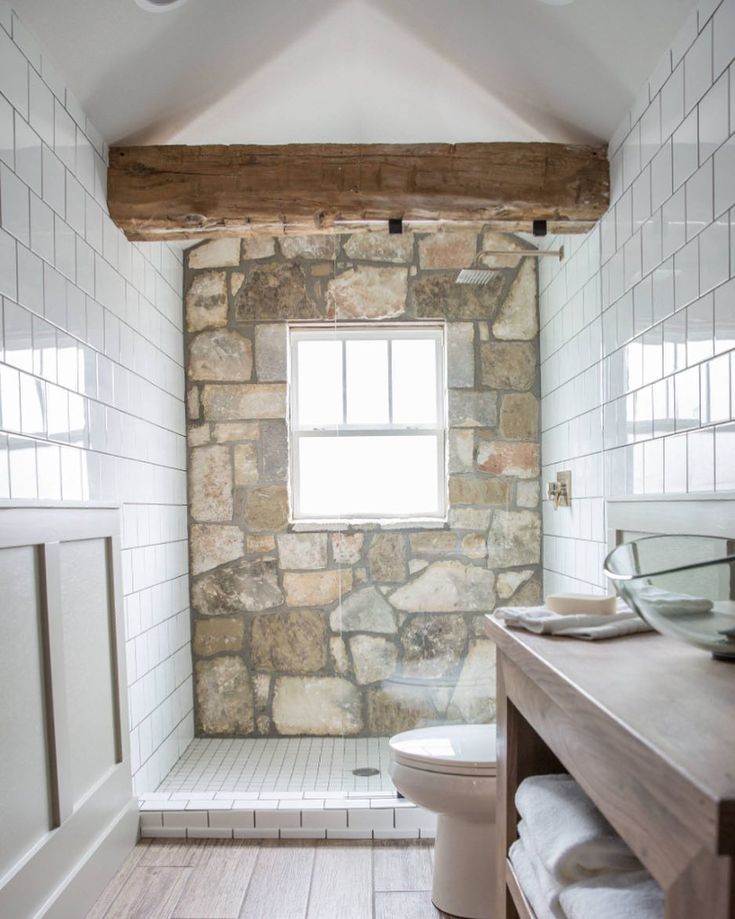 a bathroom with a stone wall and wooden flooring, along with a white toilet