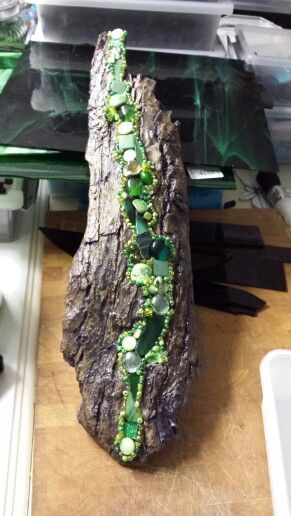 a piece of wood with green glass beads on it sitting on top of a table