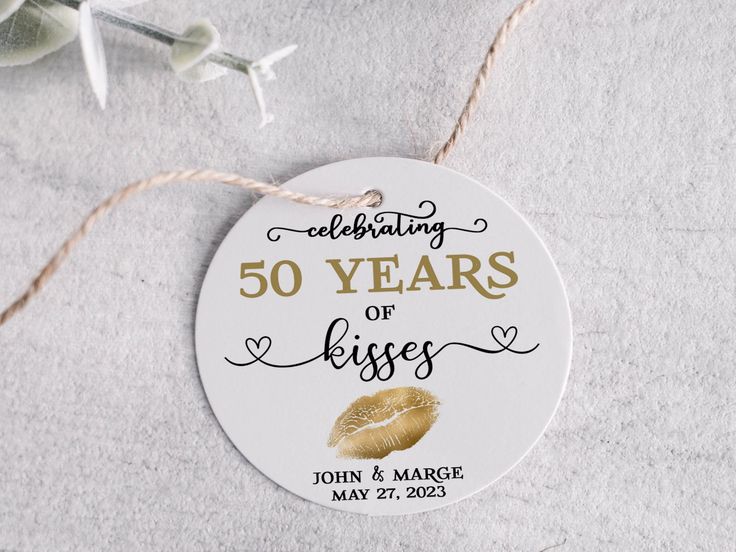 a 50th anniversary ornament hanging from a string on top of a white surface