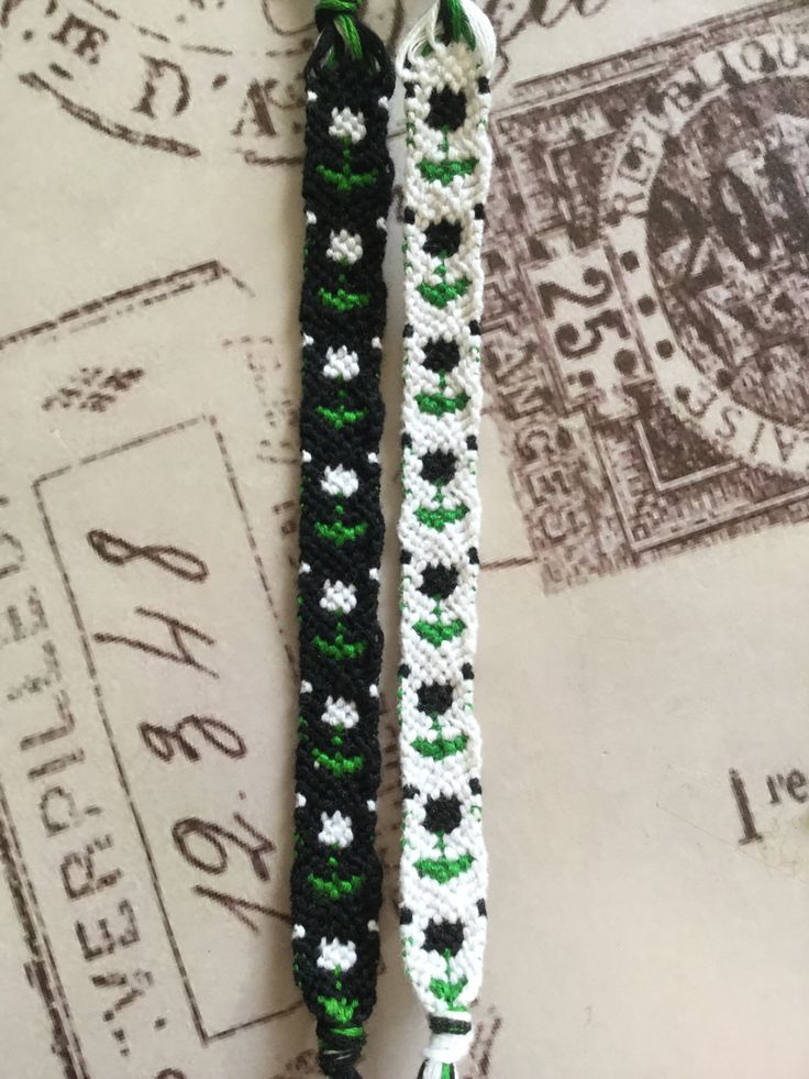 two black and white crocheted bracelets on top of a postage stamp with green accents