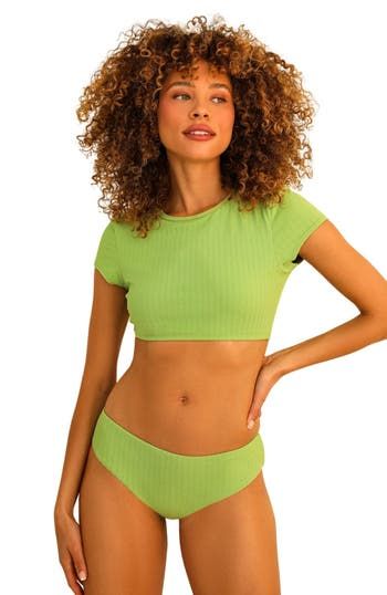 Our Joni Top is the perfect poolside crop! With a flirty bikini fit, you’ll be sure to turn heads wherever you go. Looks great paired with any of your favorite bikini bottoms – it’s the ideal choice for a sizzling vacay under the sun! 87% Nylon 13% Spandex Imported from Vietnam Crew neckline Short cap sleeve Cropped shirt style Green Short Sleeve Swimwear With Stretch, Beachwear Crop Top For Beach Party, Trendy Cropped Swimwear For Spring, Green Short Sleeve Swimwear For Beach Season, Green Short Sleeve Swimwear For Summer, Summer Cropped Swimwear, Cropped Solid Color Swimwear For Summer, Summer Crop Top For Beach, Solid Crop Top For Beach In Summer