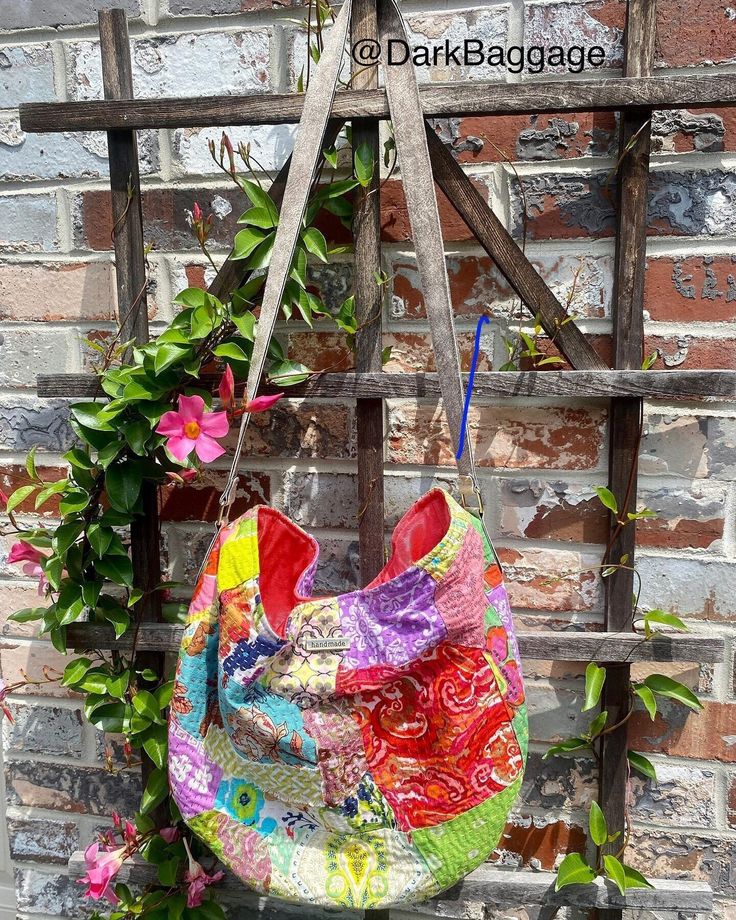 a colorful bag hanging on a brick wall next to a wooden ladder with flowers in it