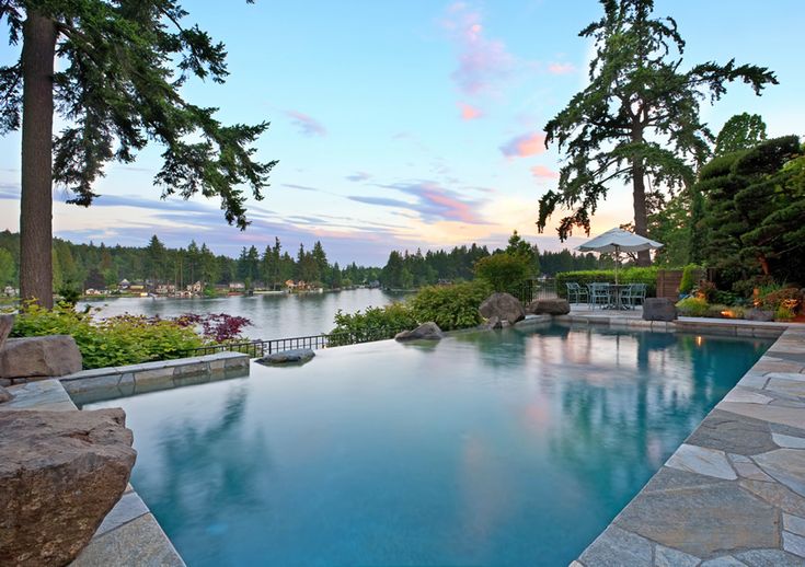 an outdoor swimming pool surrounded by trees and water