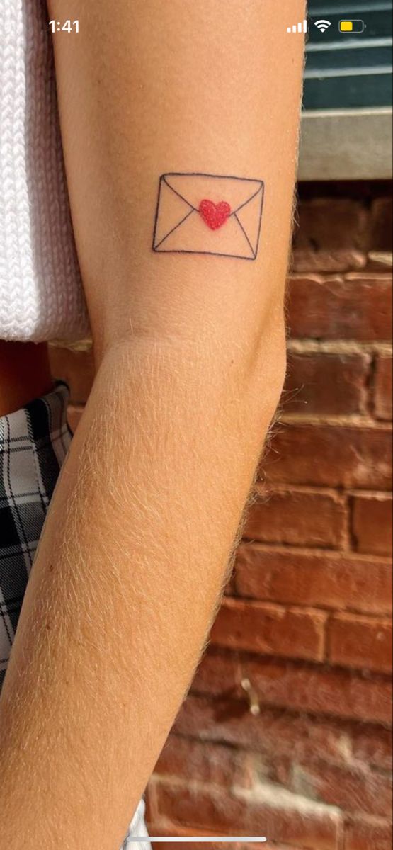 a woman's arm with an envelope and heart tattoo on the left side of her arm