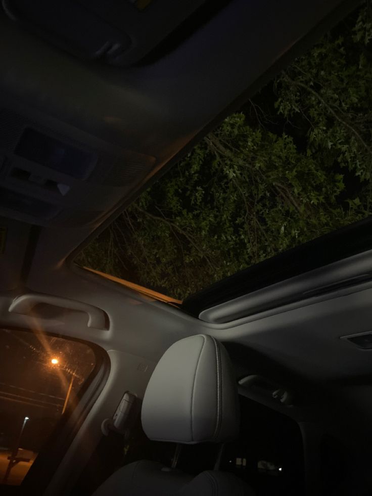 the interior of a car with its sunroof and dashboard lights on at night