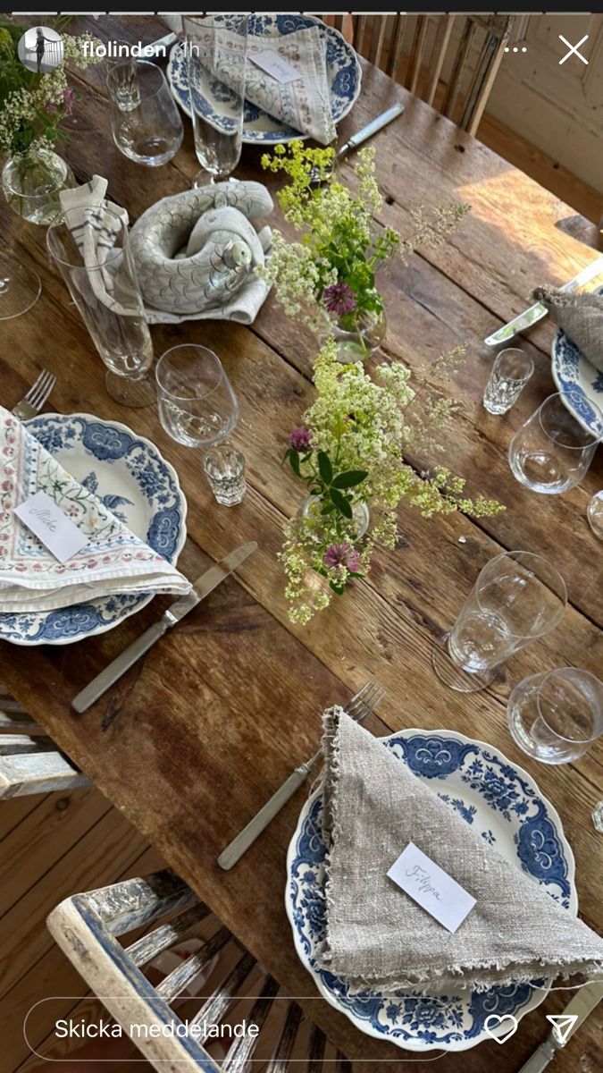 a wooden table topped with blue and white plates covered in napkins next to flowers