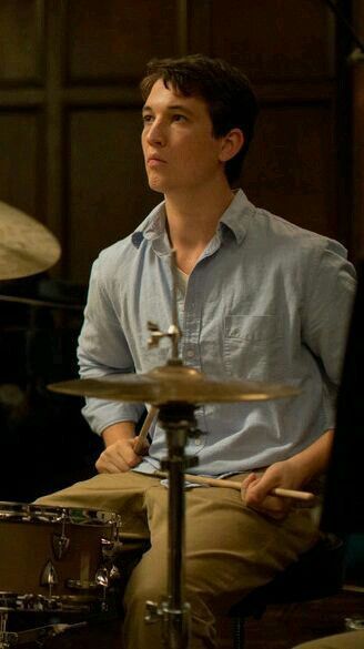 a man sitting in front of a drum set