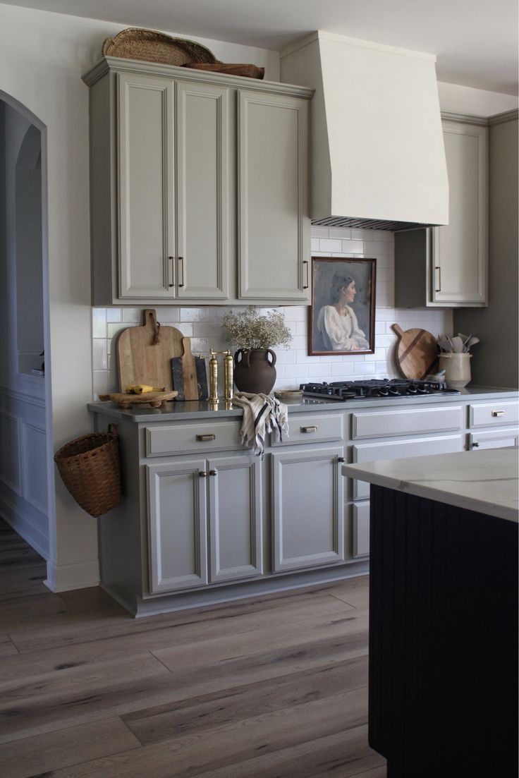 a kitchen with white cabinets and wood floors