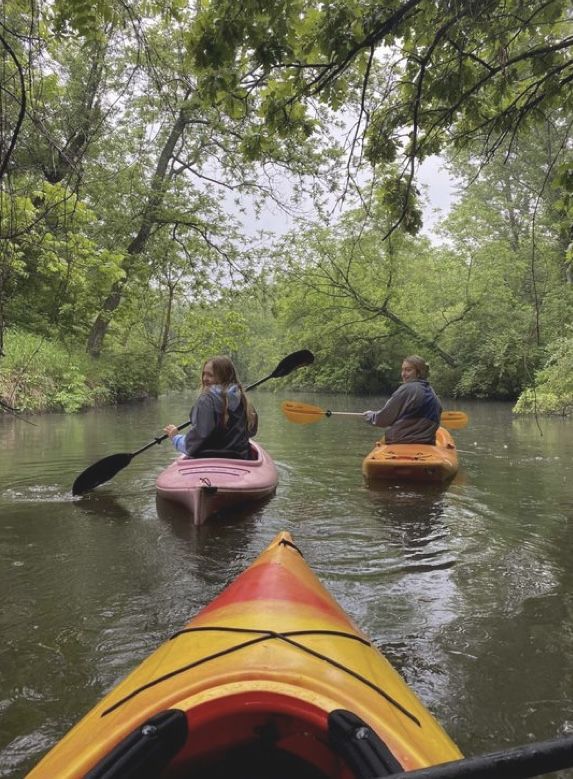 two people in kayaks paddling down a river