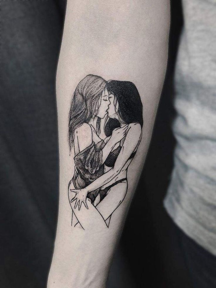 a woman's arm with a black and white drawing of two women hugging each other