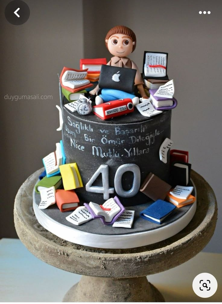 a birthday cake decorated with books and laptops