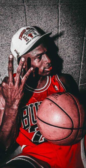 a man sitting on the floor with his hand up to his face while holding a basketball