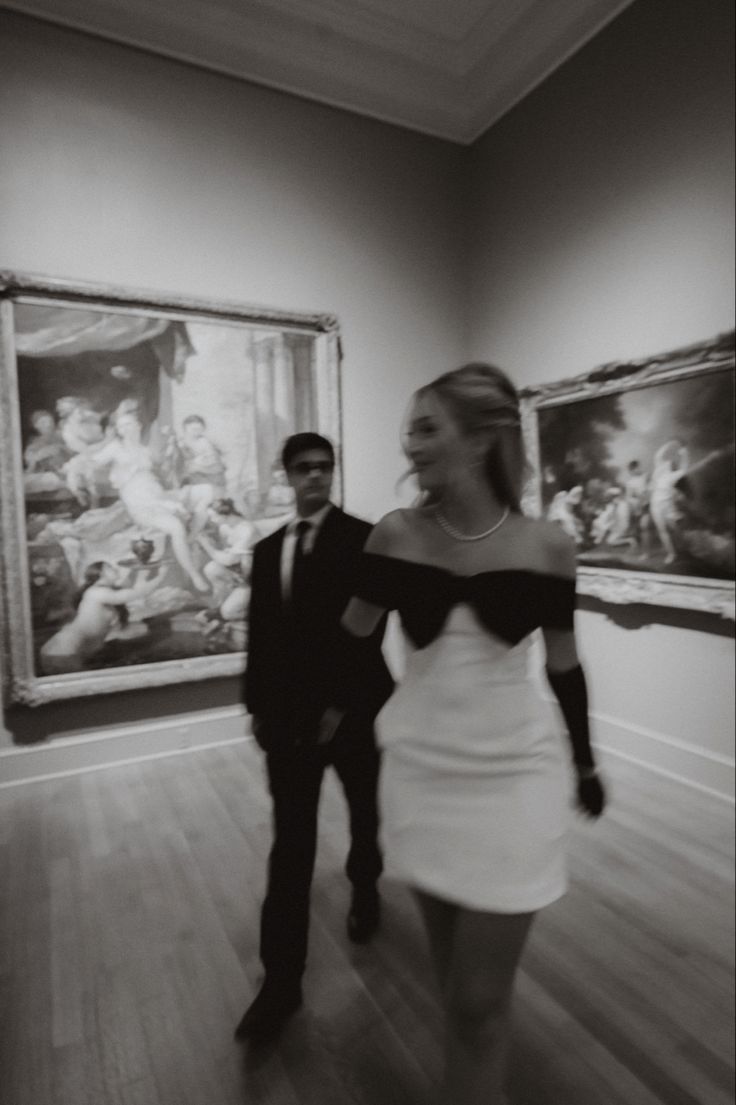 a man and woman walking through an art gallery