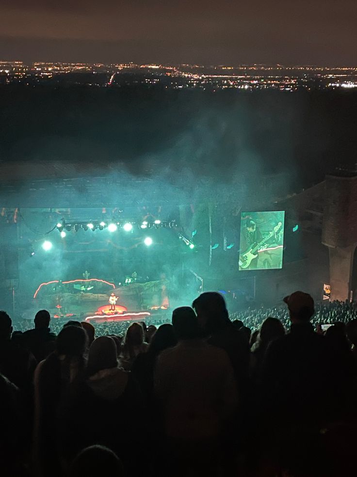 a large group of people at a concert watching a show on the big screen in front of an audience