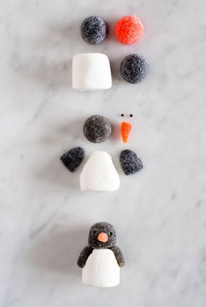 three marshmallows are arranged in the shape of a penguin and an orange carrot