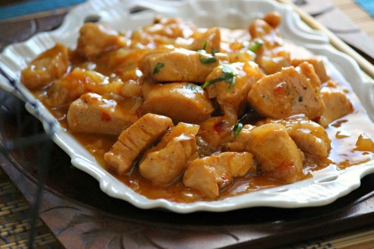 a white plate topped with meat covered in gravy next to chopsticks