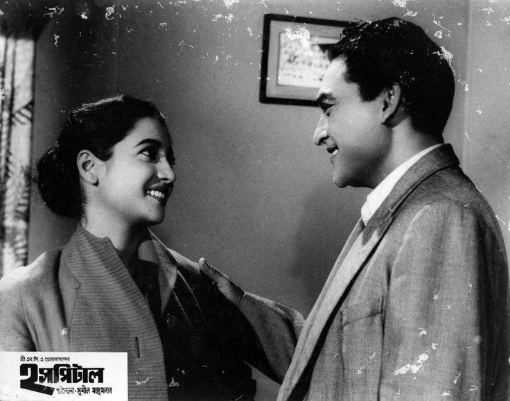 an old black and white photo of two people talking to each other in front of a window