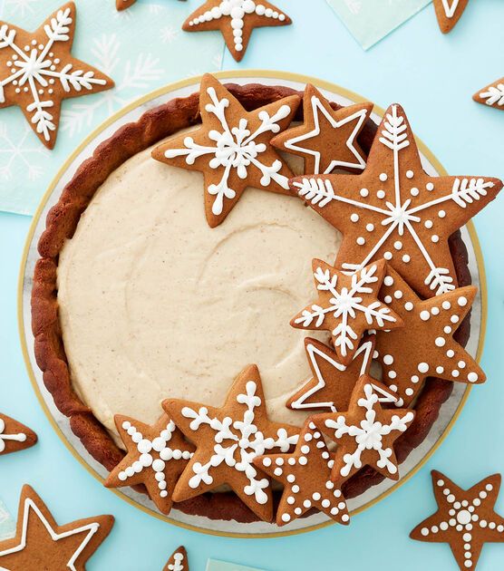 there is a pie with icing and decorated cookies on it