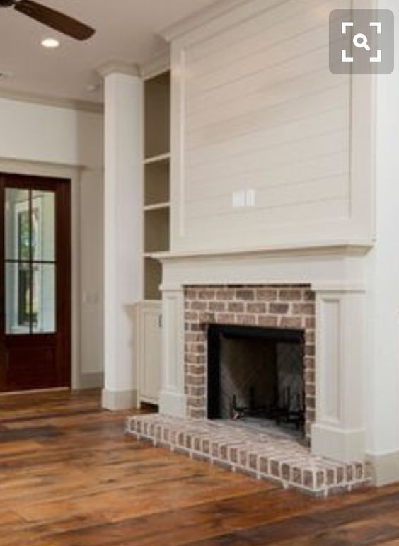 an empty living room with a fireplace and built in bookshelves