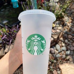 a hand holding a starbucks cup with a straw in it