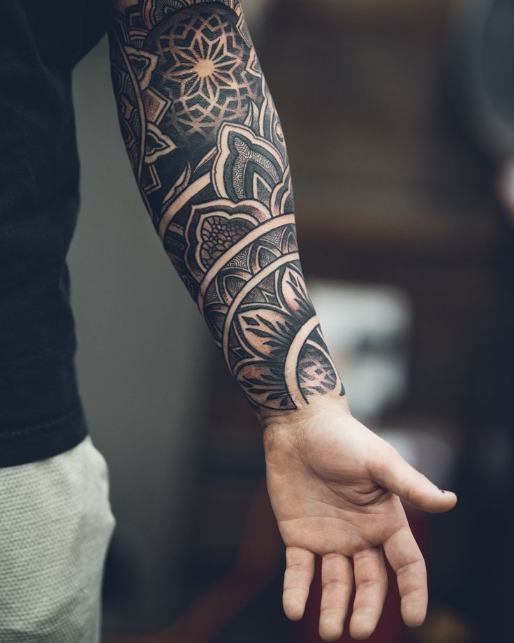 a person with a tattoo on their arm holding his hand out to the side while wearing a black t - shirt