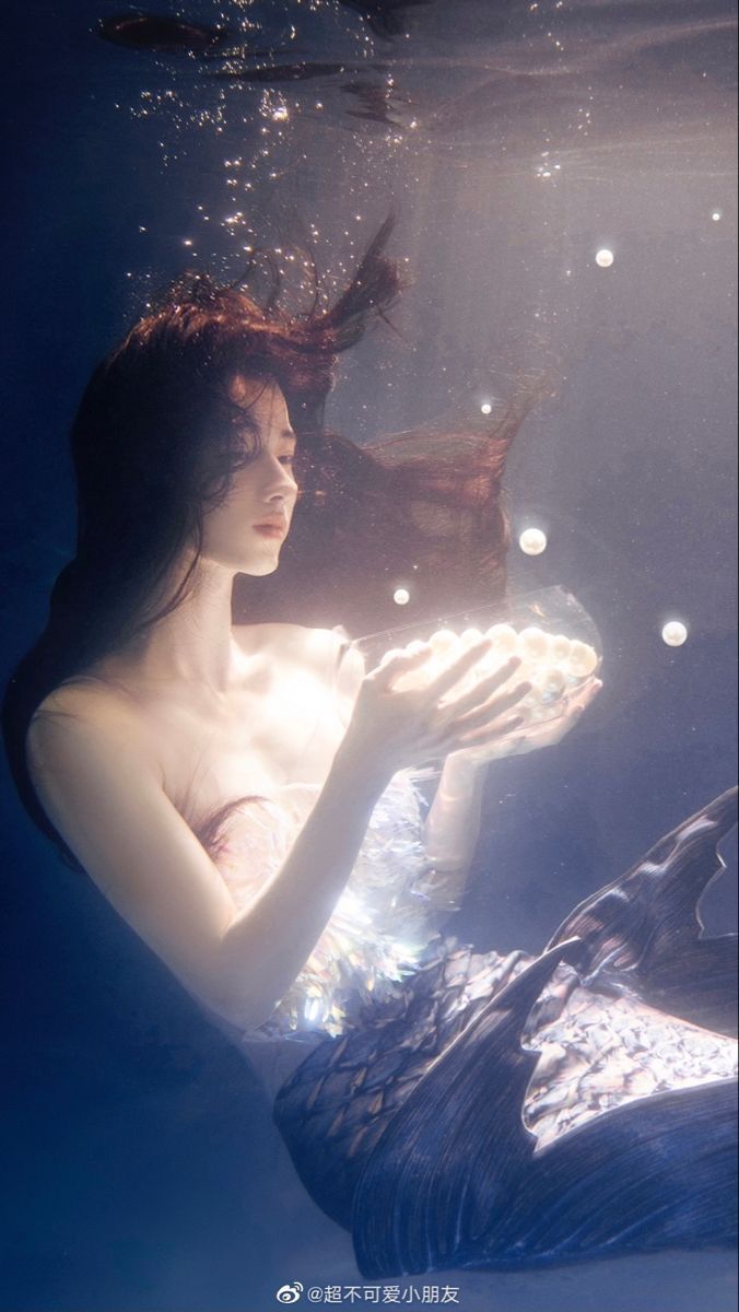 a woman in a white dress is under water holding a plate with fish on it