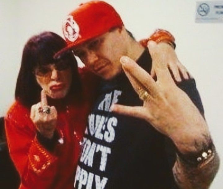 a man and woman posing for the camera with their fingers in the shape of two peace signs