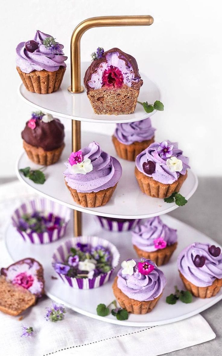 a three tiered plate with cupcakes and muffins on the side