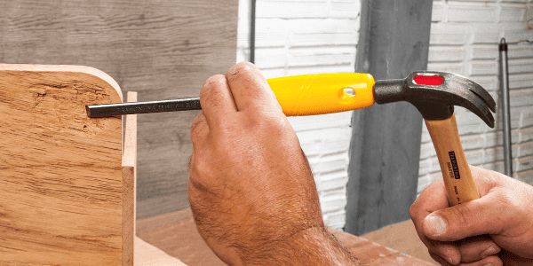 a man holding a hammer over a piece of wood