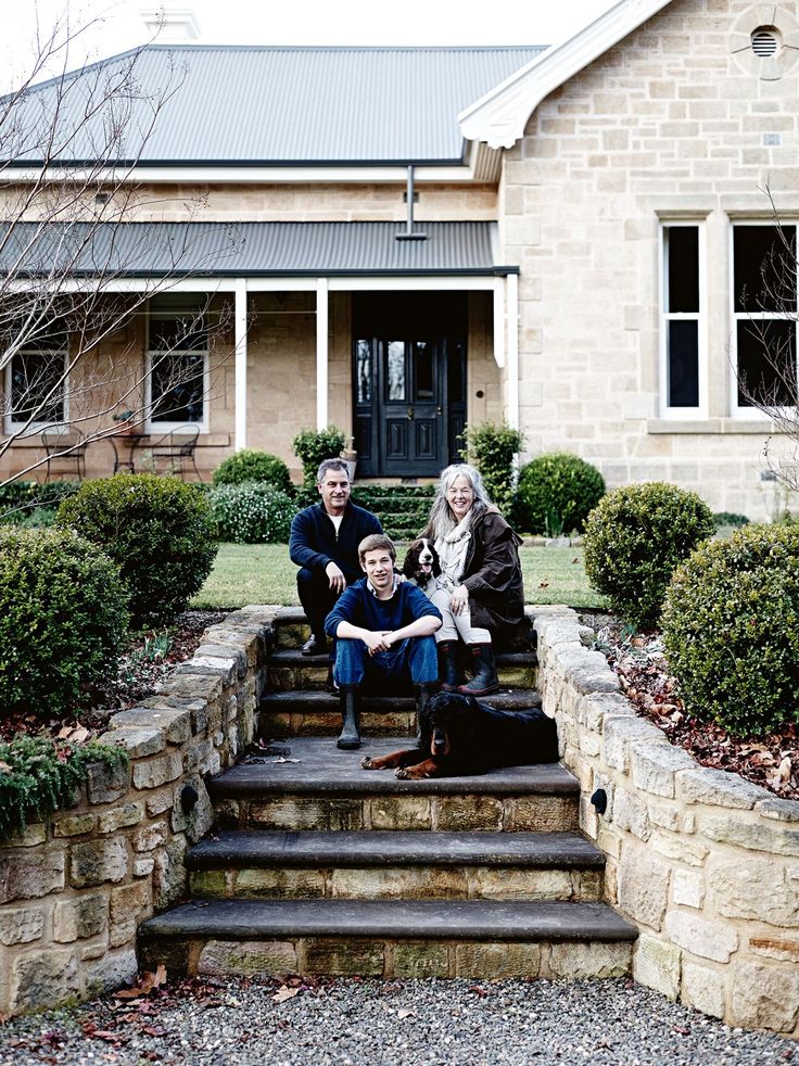 three people sitting on steps in front of a house