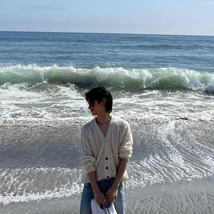 a man standing on the beach holding a bag