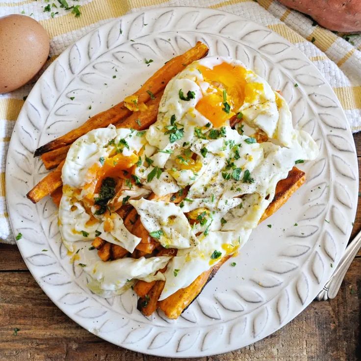 a white plate topped with an egg and french fries on top of a wooden table