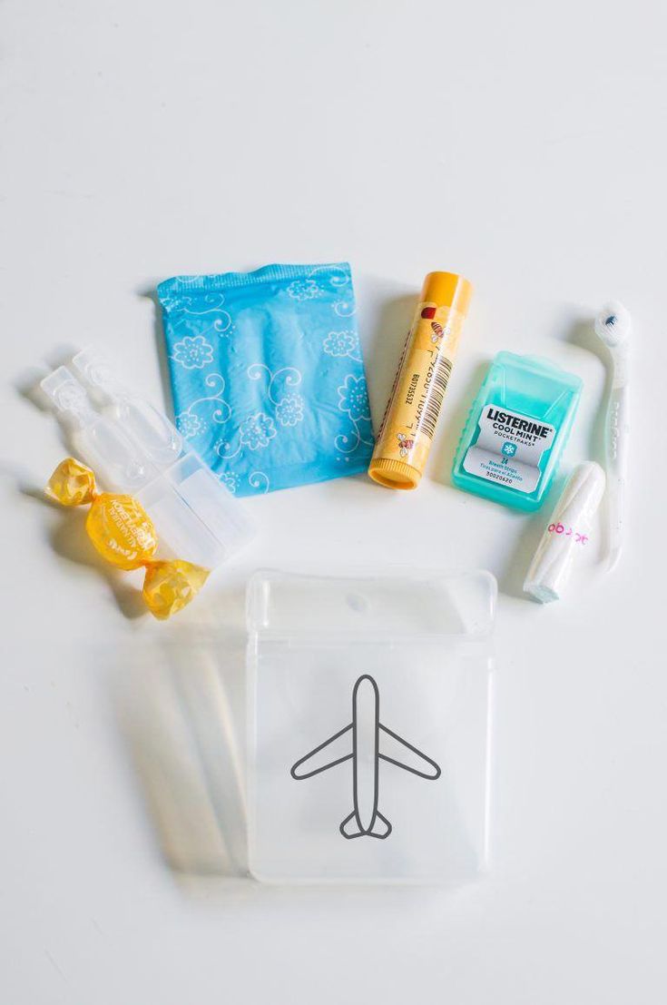 the contents of an airplane travel kit laid out on a white surface, including toothpaste, wipes, and other items