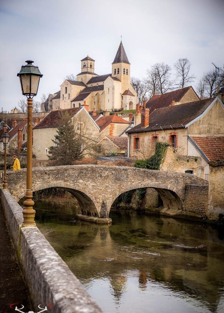 an old stone bridge over a river in front of some buildings and a lamp post