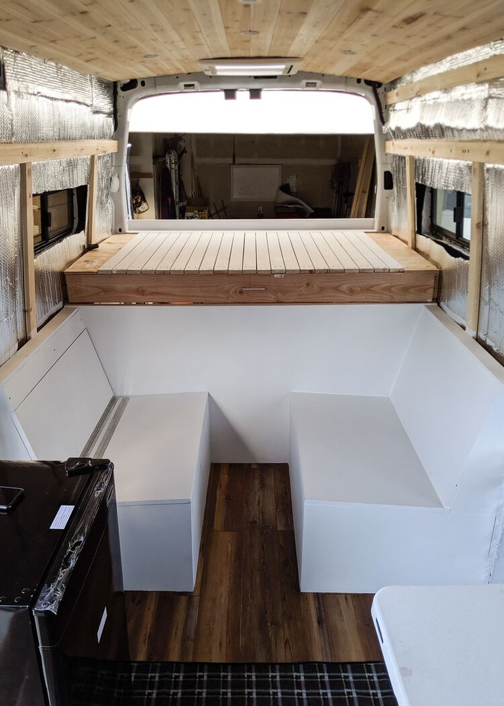 the inside of a truck with wood flooring and white walls, including an area for storage