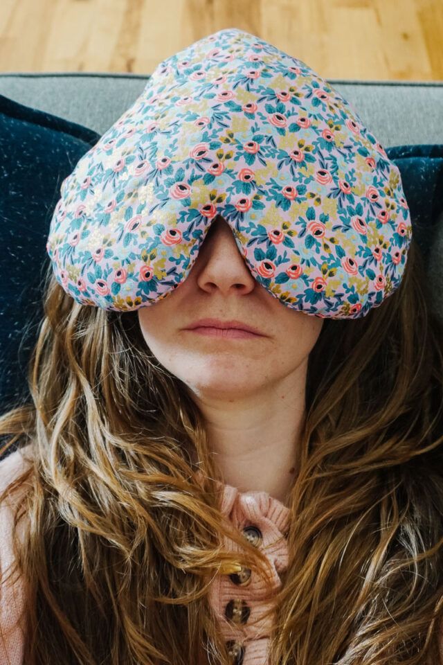 a woman with long hair wearing a pillow over her eyes